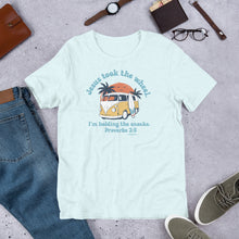 Load image into Gallery viewer, Light blue t-shirt with a graphic and text on a gray surface with jeans, shoes, and accessories.